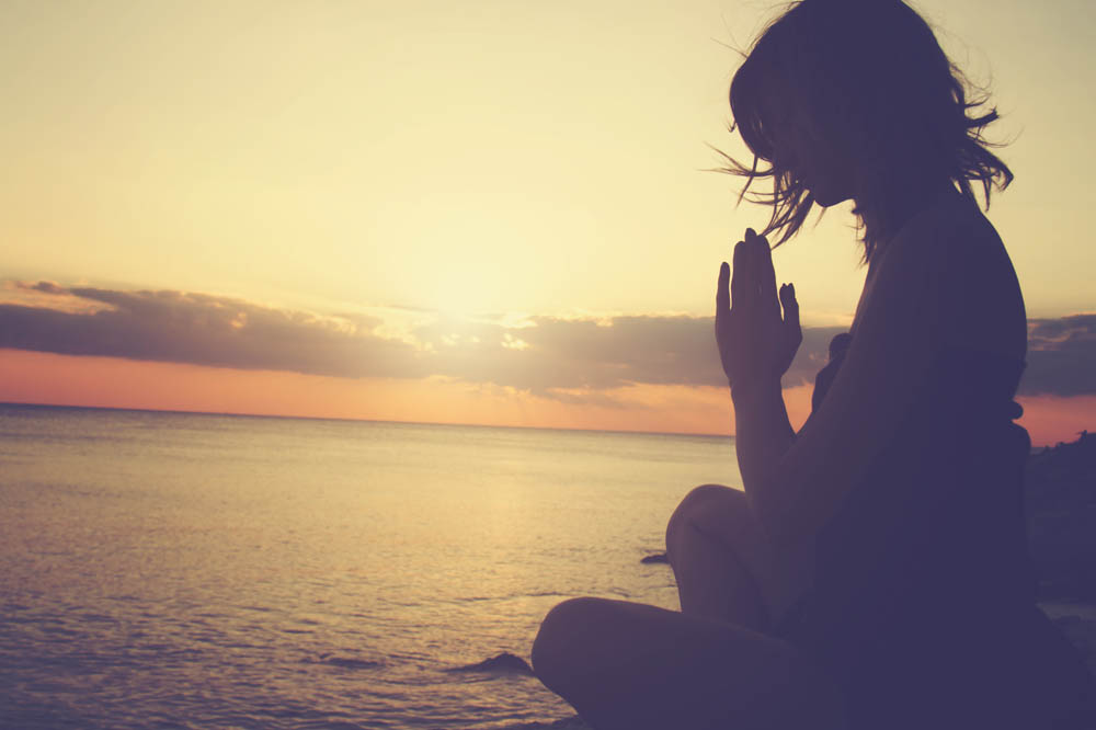 Young woman practicing yoga on the beach.